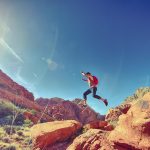 Man jumping while hiking among rock formations