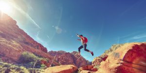 Man jumping while hiking among rock formations