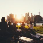 A group of women sitting in a circle for a picnic in a park outside a city