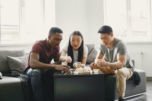 Three people sitting around a table playing with wooden blocks