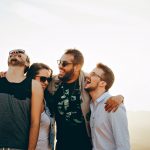 Four people are laughing and wearing sunglasses or glasses