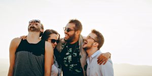 Four people are laughing and wearing sunglasses or glasses