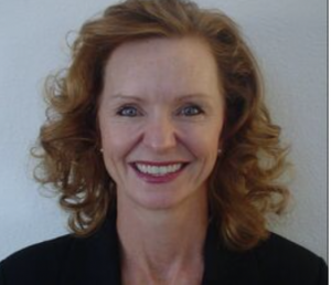 a close up a smiling white women with shoulder length red curly hair, wearing a black shirt