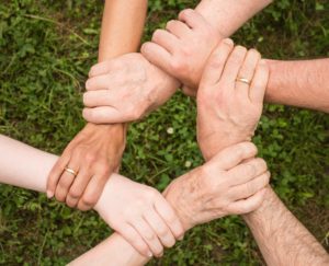 six hands of different shapes, sizes, colors joined together at the wrist