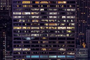 Tall skyscraper building, at night, with many office spaces and rooms with the lights turned on.