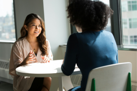 Two women sitting in chairs around a table